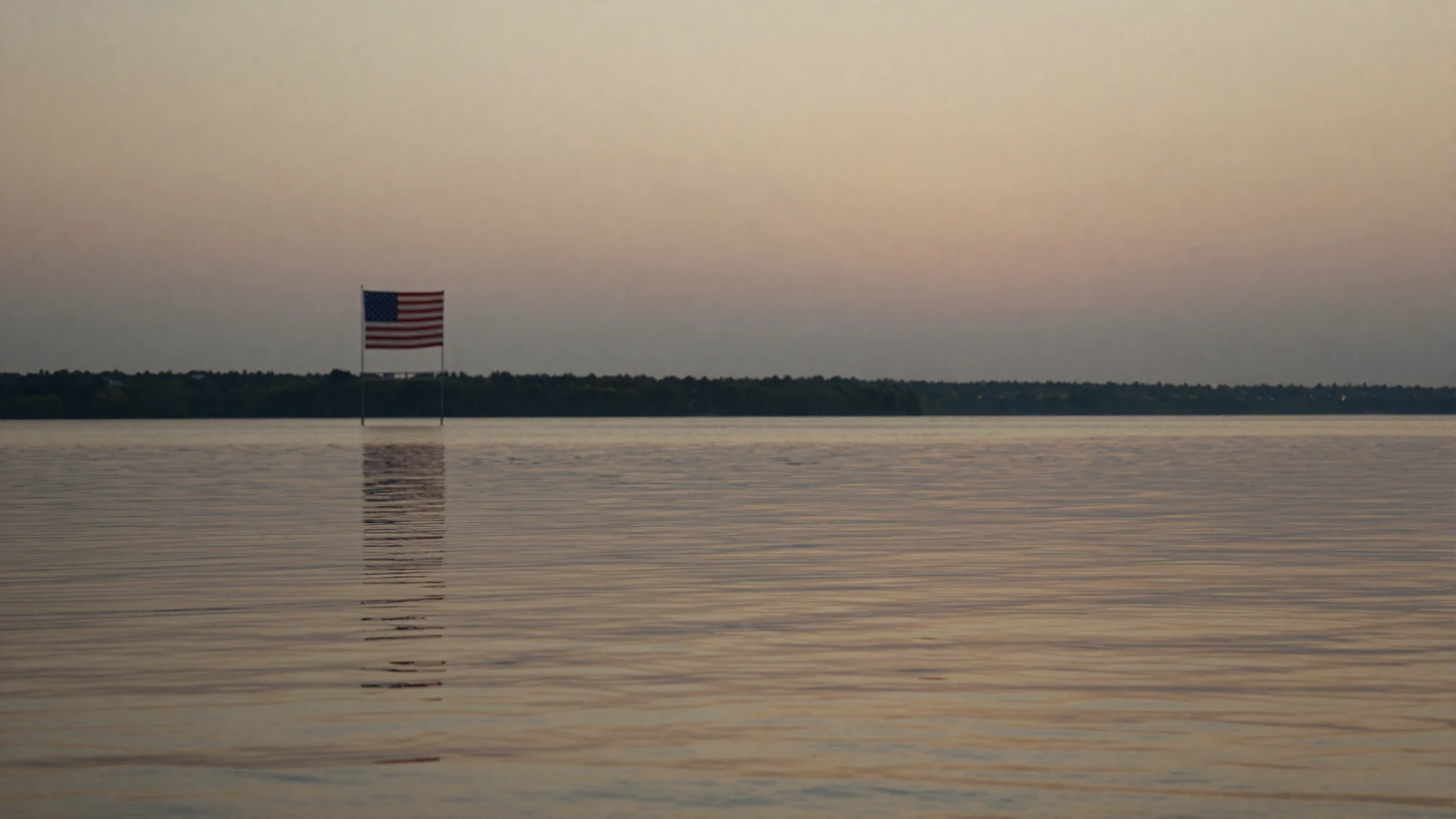 Calm dusk waterfront with a softly blurred American flag, representing privacy on the HonorElite military dating site